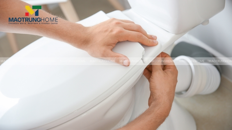 Vặn lỏng hai con ốc chốt ở phía sau bệ ngồi và nhấc nắp cũ ra